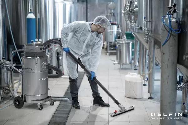 Mann mit Industriesauger von Delfin saugt in der Pharma- oder Lebensmittelindustrie